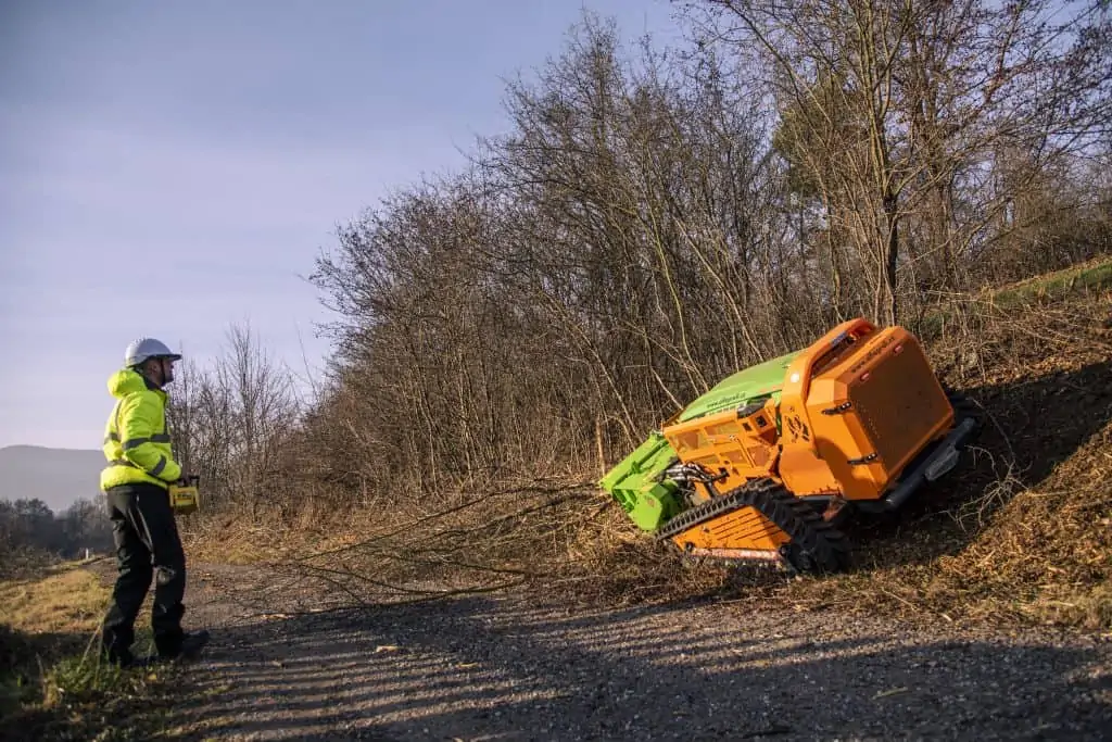 GreenClimber pri práci na svahu, kde odstraňuje náletové dreviny a prerastenú vegetáciu popri ceste.